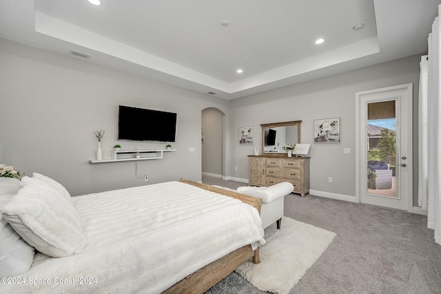 carpeted bedroom with a raised ceiling and access to outside