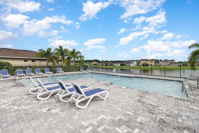 view of swimming pool featuring a water view and a patio