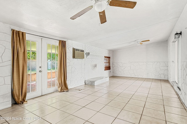 tiled spare room with a textured ceiling, a wall mounted AC, ceiling fan, and french doors