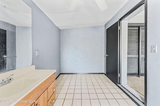 bathroom featuring tile patterned flooring, ceiling fan, vaulted ceiling, and vanity