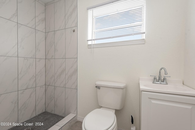 bathroom featuring tiled shower, toilet, and vanity