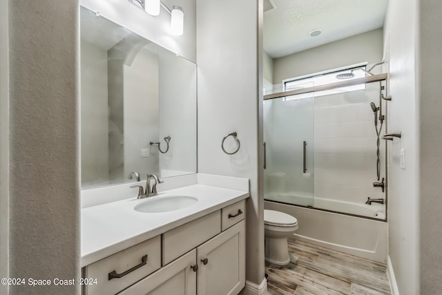 full bathroom featuring hardwood / wood-style floors, vanity, enclosed tub / shower combo, and toilet