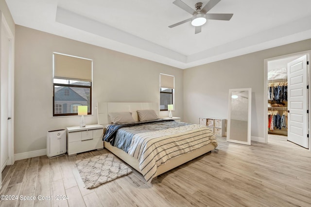7356 Millbrook Ave, Melbourne, FL 32940 - bedroom with a closet, a tray ceiling, light wood-style flooring, baseboards, and a spacious closet