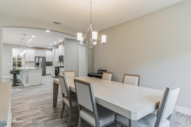7356 Millbrook Ave, Melbourne, FL 32940 - dining room with an inviting chandelier, light wood-type flooring, visible vents, arched walkways, and recessed lighting