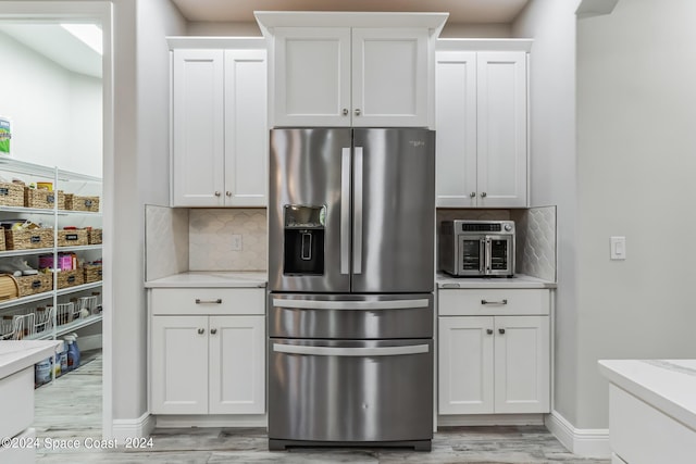 7356 Millbrook Ave, Melbourne, FL 32940 - kitchen with light wood finished floors, stainless steel refrigerator with ice dispenser, white cabinets, baseboards, and backsplash