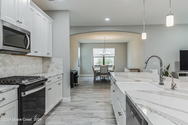 7356 Millbrook Ave, Melbourne, FL 32940 - kitchen with appliances with stainless steel finishes, white cabinetry, decorative backsplash, arched walkways, and light wood-style floors