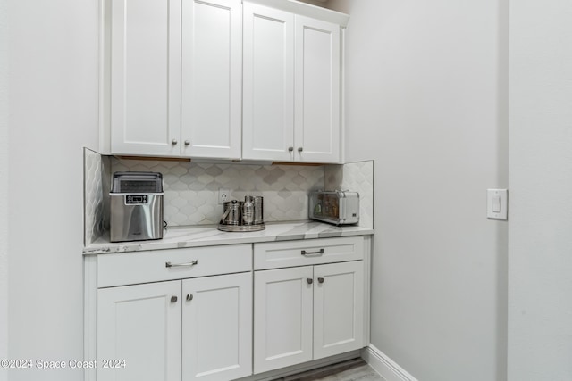 kitchen featuring backsplash, light stone countertops, white cabinets, and light hardwood / wood-style floors