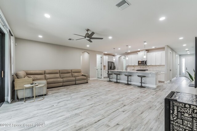 living room with ceiling fan, sink, and light hardwood / wood-style flooring