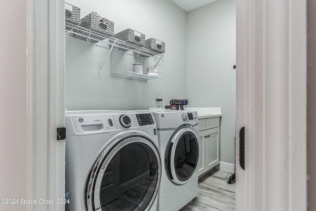 laundry area featuring cabinets, light hardwood / wood-style flooring, and washer and clothes dryer