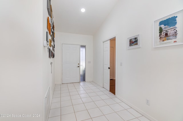 hallway with light tile patterned flooring and vaulted ceiling