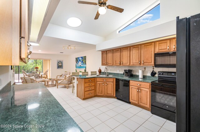 kitchen featuring black appliances, sink, backsplash, light tile patterned floors, and kitchen peninsula