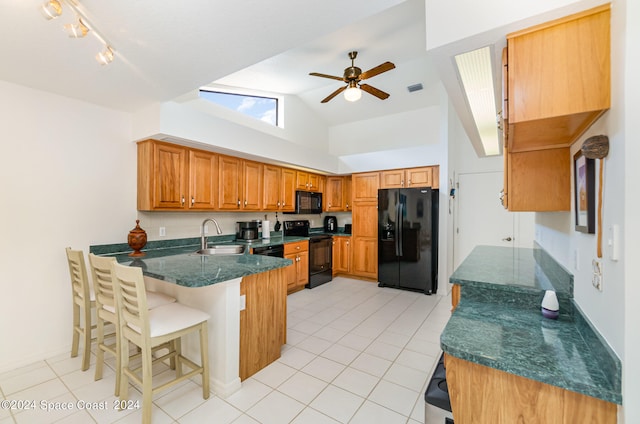 kitchen with light tile patterned flooring, kitchen peninsula, sink, and black appliances