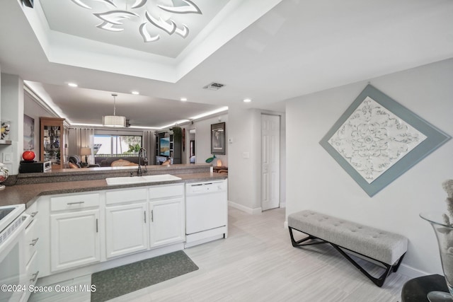 kitchen with sink, a raised ceiling, pendant lighting, white appliances, and white cabinets