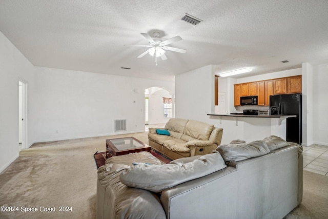 living room with ceiling fan, light colored carpet, and a textured ceiling