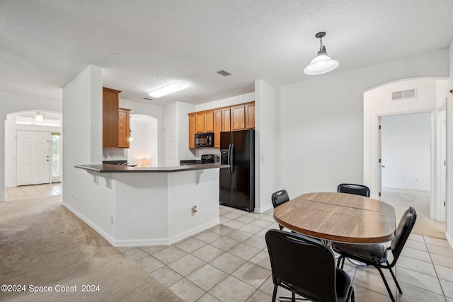 kitchen featuring a textured ceiling, kitchen peninsula, light carpet, a kitchen breakfast bar, and black appliances