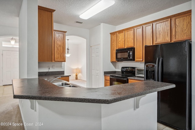 kitchen with black appliances, kitchen peninsula, a breakfast bar area, and sink