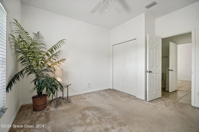 unfurnished bedroom featuring ceiling fan, light colored carpet, and a closet