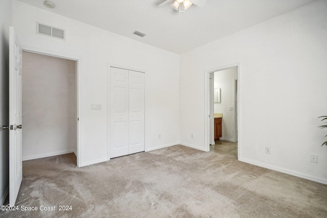 unfurnished bedroom featuring ceiling fan, a closet, light carpet, and ensuite bathroom