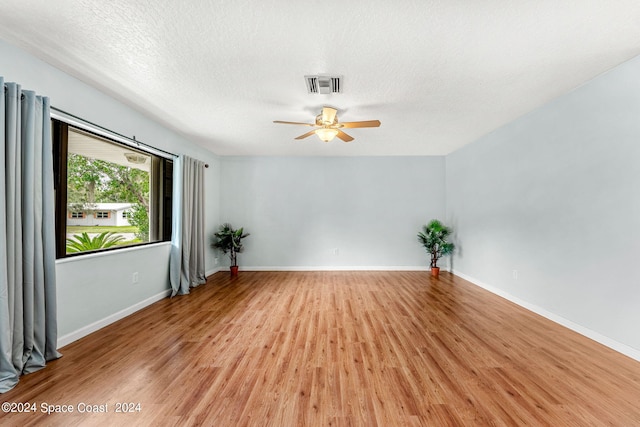 spare room with a textured ceiling, ceiling fan, and light hardwood / wood-style floors