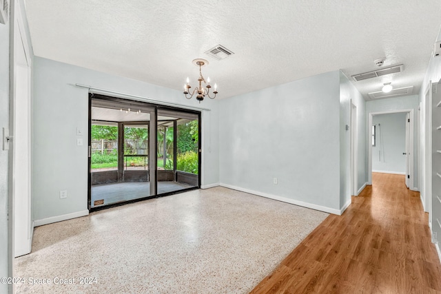 unfurnished room with an inviting chandelier and a textured ceiling