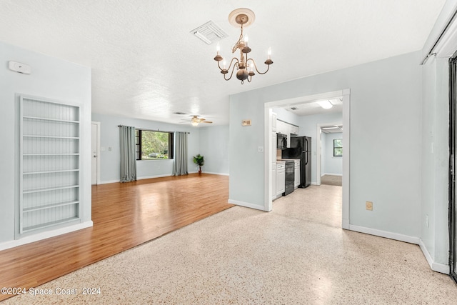 unfurnished room with ceiling fan with notable chandelier and a textured ceiling