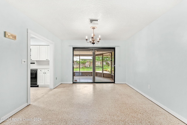 empty room featuring a textured ceiling and a chandelier