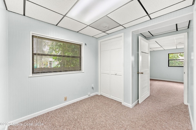 unfurnished room with a paneled ceiling and light colored carpet