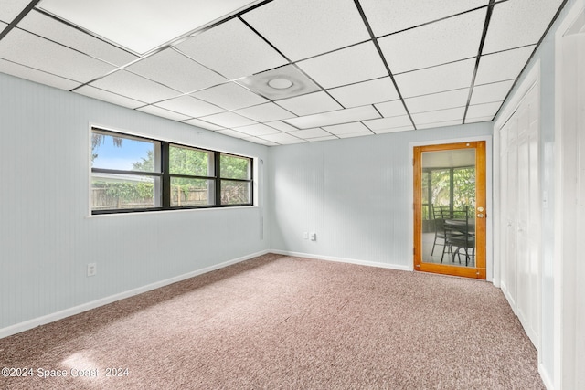 carpeted empty room with a drop ceiling and a healthy amount of sunlight