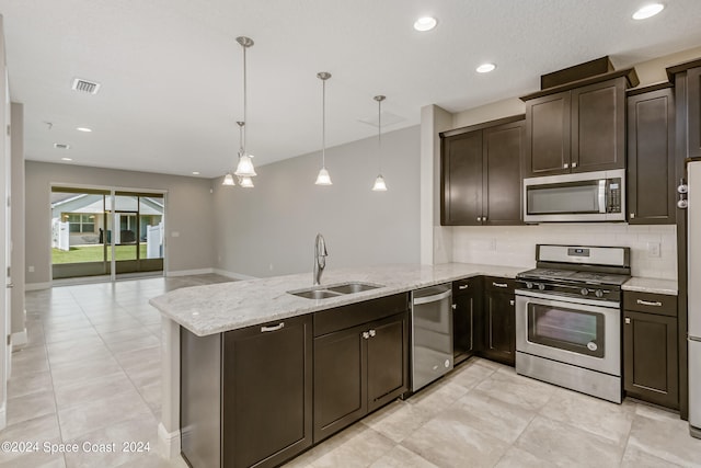 kitchen featuring pendant lighting, dark brown cabinets, stainless steel appliances, kitchen peninsula, and sink