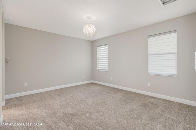 unfurnished room with a chandelier and light colored carpet