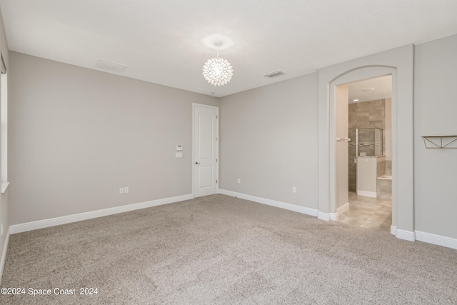 unfurnished bedroom with ensuite bathroom and light colored carpet