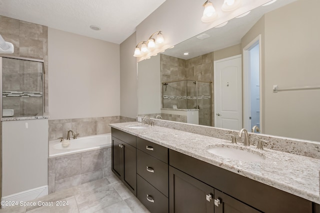 bathroom with a textured ceiling, vanity, and independent shower and bath