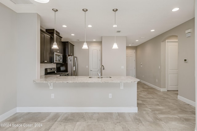 kitchen featuring pendant lighting, kitchen peninsula, sink, light stone countertops, and appliances with stainless steel finishes