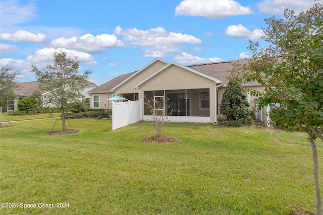 rear view of property featuring a yard and a sunroom