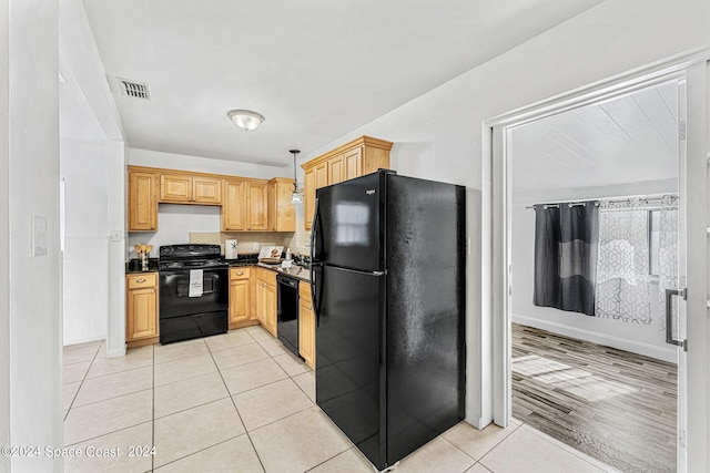 kitchen featuring black appliances, decorative light fixtures, light brown cabinets, and light hardwood / wood-style flooring