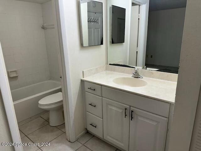 full bathroom with tile patterned flooring, tiled shower / bath combo, vanity, and toilet