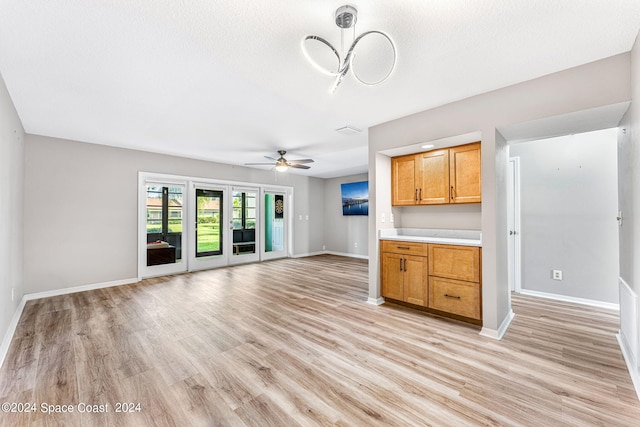 unfurnished living room featuring ceiling fan, light hardwood / wood-style floors, and a textured ceiling