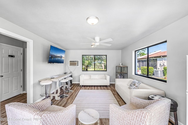 living room with an AC wall unit, a wealth of natural light, ceiling fan, and dark wood-type flooring