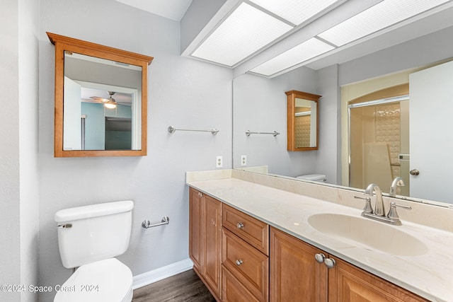 bathroom with ceiling fan, walk in shower, toilet, vanity, and hardwood / wood-style flooring