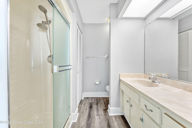 bathroom featuring vanity, hardwood / wood-style flooring, toilet, and a shower with shower door