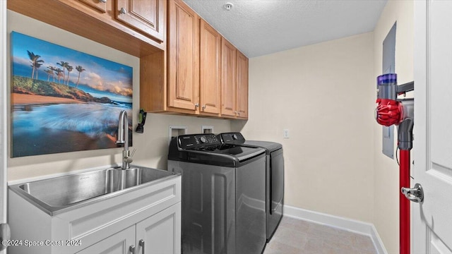 laundry area featuring washer and dryer, a textured ceiling, and cabinets