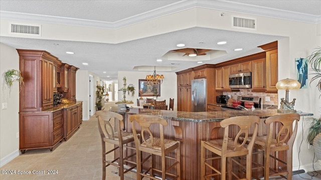 kitchen with kitchen peninsula, stainless steel appliances, ornamental molding, a breakfast bar, and a textured ceiling