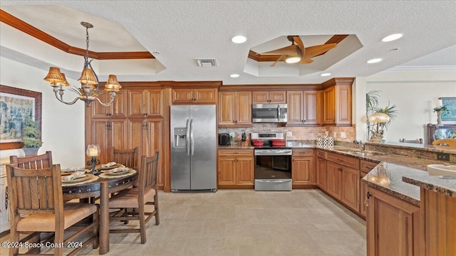 kitchen with backsplash, appliances with stainless steel finishes, a tray ceiling, crown molding, and decorative light fixtures