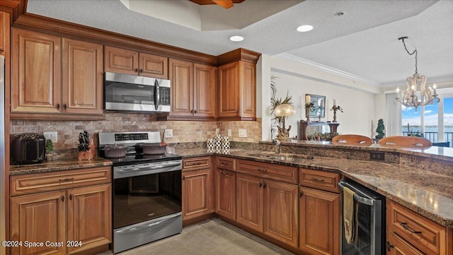 kitchen with stainless steel appliances, ornamental molding, a notable chandelier, beverage cooler, and a textured ceiling