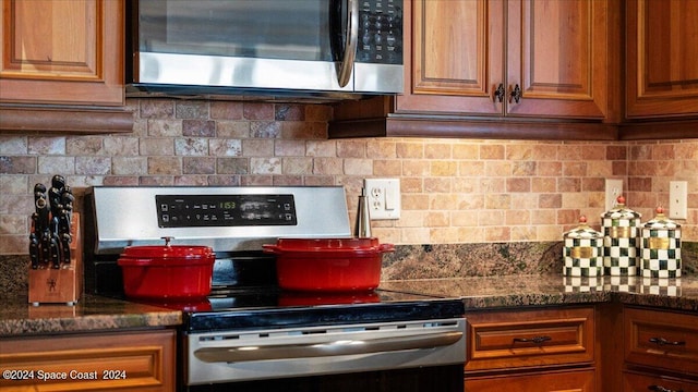 kitchen with dark stone countertops, stainless steel appliances, and tasteful backsplash