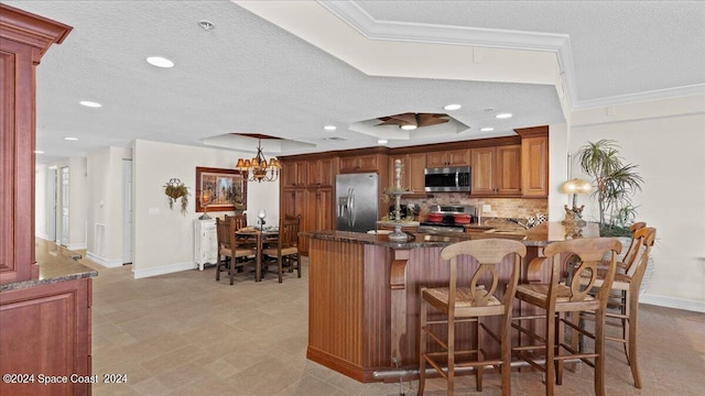 kitchen with kitchen peninsula, hanging light fixtures, backsplash, appliances with stainless steel finishes, and a notable chandelier