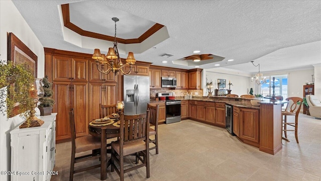 kitchen featuring stainless steel appliances, a raised ceiling, kitchen peninsula, and hanging light fixtures