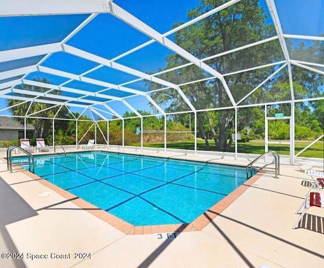 view of pool featuring glass enclosure and a patio area