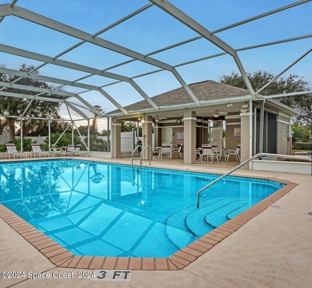 view of swimming pool featuring glass enclosure, an outbuilding, and a patio