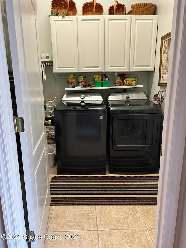 laundry area with separate washer and dryer, light tile patterned floors, and cabinets